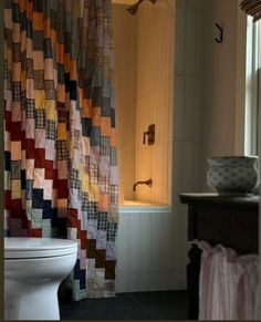 a bath room with a toilet and a bath tub next to a curtained window