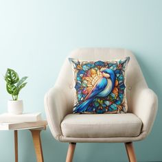 a blue bird pillow sitting on top of a chair next to a potted plant