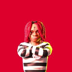 a woman with red dreadlocks standing in front of a red background wearing a striped shirt