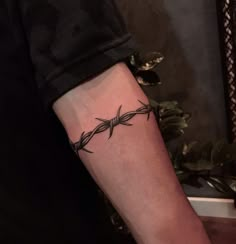 a black and white photo of a person's arm with a barbed wire tattoo on it