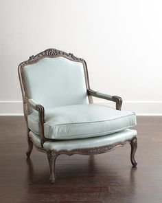 an old fashioned chair sitting on top of a hard wood floor next to a white wall