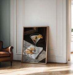 a painting of a martini glass and crackers on a table next to a chair