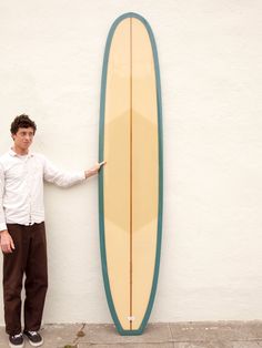 a man standing next to a surfboard on the side of a building