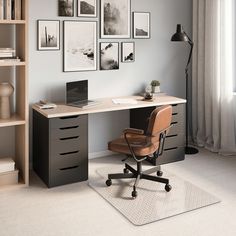 a desk with a chair and some pictures on the wall above it, in front of a window