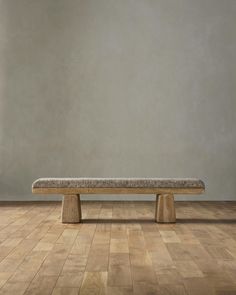 a wooden bench sitting on top of a hard wood floor next to a gray wall