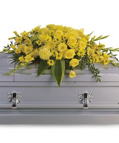 a silver casket filled with yellow flowers and greenery