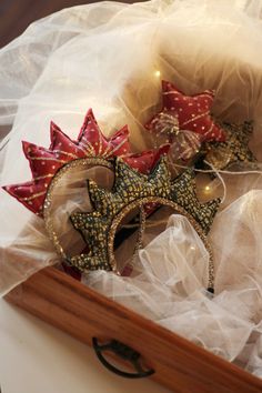 two red and gold stars are on top of each other in a wooden box with white netting