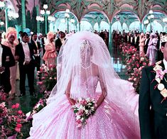 a man and woman dressed in wedding gowns standing next to each other with flowers on the floor