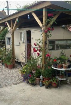 an old trailer is covered with flowers and potted plants