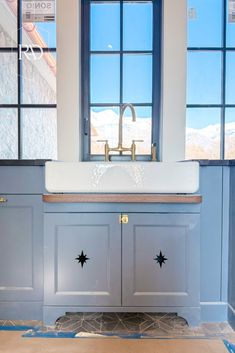 a bathroom sink sitting under a window in front of a blue painted wall and floor