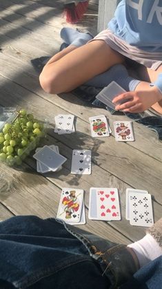 a person sitting on the ground with some cards and grapes in front of them,