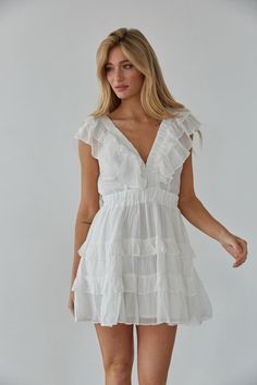 Embrace your femininity in the Xena Flutter Sleeve Babydoll Mini Dress! This mini dress features flutter sleeves, a V-neckline, tiered ruffle skirt, and a triple clasp bust detail. Available in white and blue. Pair with some heels to complete the look! Details 75% Rayon, 25% Nylon Lining: 100% Polyester Elastic waistband Elastic band sleeves Hand wash cold Flowy V-neck Dress With Ruffles For Summer, Chic White V-neck Tiered Dress, Feminine V-neck Tiered Summer Dress, Feminine V-neck Dress With Ruffles And Short Sleeves, White V-neck Tiered Dress For Summer, V-neck Ruffled Sundress Mini Dress, Ruffled Mini V-neck Dress For Vacation, Flowy V-neck Ruffle Dress, Ruffled Flutter Sleeve Mini Dress For Vacation