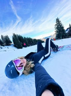 a person laying on the snow with skis and goggles