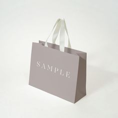 a gray shopping bag with the word sample on it's front and white handles