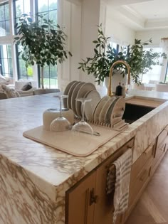 a kitchen counter with plates and glasses on it, in the middle of a living room