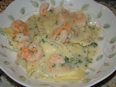 a white plate topped with pasta covered in shrimp