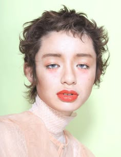 a woman with short hair and orange lipstick