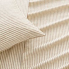 a close up of a pillow on a bed with striped sheets and pillows in the background