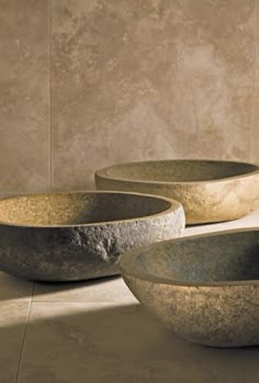 three stone bowls sitting on top of a floor next to each other in front of a wall