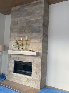 a living room with a stone fireplace and blue tarp on the floor next to it