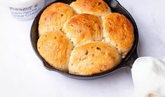 a pan filled with rolls next to a cup of coffee and napkin on a table