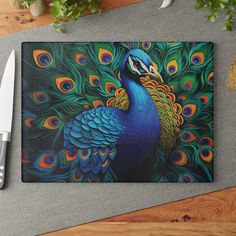 a colorful peacock with feathers on it's back is next to a knife and cutting board