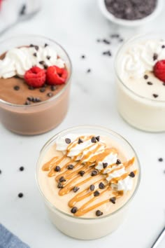 three desserts with whipped cream, chocolate chips and raspberries in small bowls