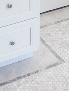 a white bathroom with hexagonal tile flooring and drawers on either side of the bathtub