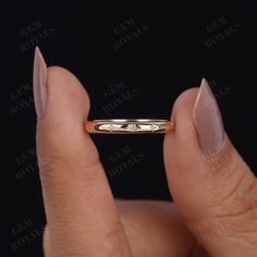 a woman's hand holding a gold ring with diamonds on the inside and outside