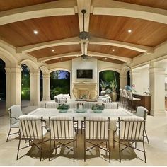 an outdoor dining area with white chairs and wooden ceiling beams, surrounded by large windows