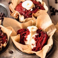 three cupcakes with red velvet and white frosting in muffin tins