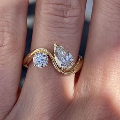 a woman's engagement ring with two pear shaped diamonds