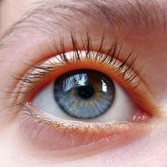 a close up of an eye with orange and blue colors on it's iris