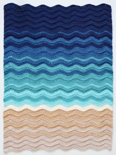 a crocheted blanket with waves in blue, brown and tan colors on it