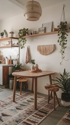 a table and two chairs in a room with plants on the wall behind it,