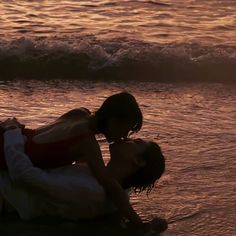 two people in the water with their arms around each other and one person laying on his back