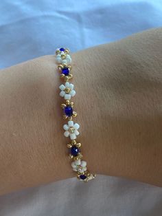 a woman's arm wearing a bracelet with blue and white beads on it,