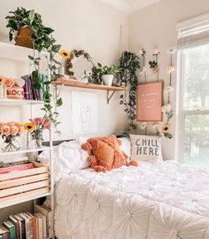 a white bed sitting in a bedroom next to a window with plants on the wall