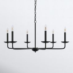 a black chandelier with six candles hanging from it