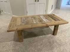 a wooden table sitting on top of a carpeted floor next to a white door