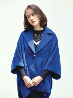 a woman wearing a blue cape and black pants