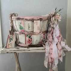 an old wooden basket sitting on top of a table next to a pink ribbon tied around it