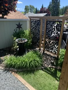 an outdoor area with grass, plants and a wooden structure on the side of it