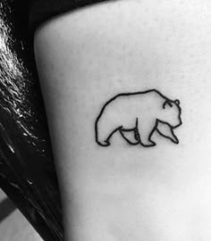 a black and white photo of a small bear tattoo on the left side of the leg