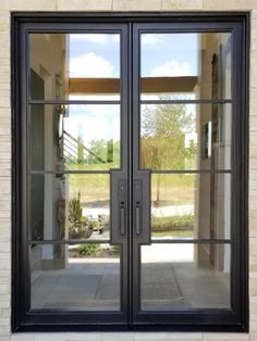 an open double glass door in front of a brick building