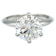 a white gold ring with a round brilliant cut diamond in the center and three prongs on each side