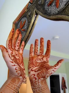 two hands are shown with henna designs on their palms and the mirror is reflecting them