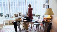 a woman in a red dress is standing at a desk with a laptop and lamp