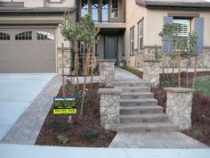 a house with stone steps leading up to the front door and landscaping area on either side