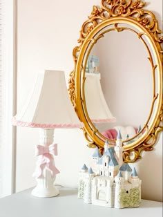 a mirror sitting on top of a white table next to a lamp and a castle